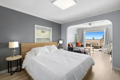 a bedroom with a white bed and a living room at 1628 West Oceanfront Oasis 1,2,3 in Newport Beach