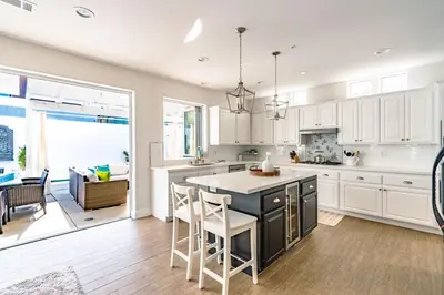 a kitchen with white cabinets and a table and chairs at Upscale Beach Cottage a Block to the Beach Sauna in Encinitas