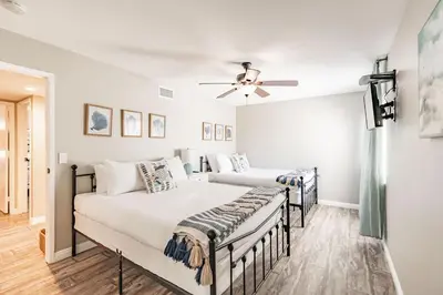 two beds in a bedroom with a ceiling fan at PB Compound Getaway Steps to Surf and Sand in San Diego