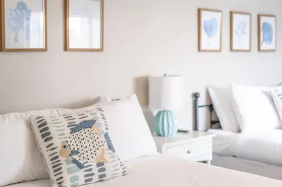 a white bed with a pillow and a couch at PB Compound Getaway Steps to Surf and Sand in San Diego