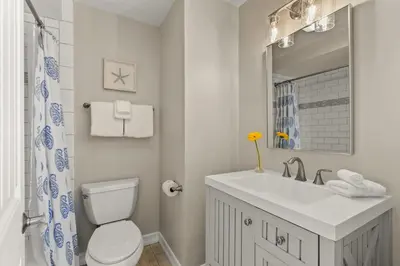 a white bathroom with a toilet and a sink at Mission Beach Marvel in San Diego
