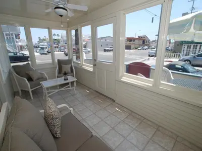 a porch with a couch and chairs and windows at Lower West Newport in Newport Beach