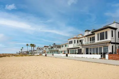 a row of houses on a beach with palm trees at 204 E Oceanfront A in Newport Beach