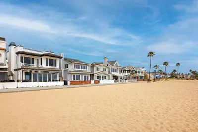 a row of houses on a beach with palm trees at 204 E Oceanfront A in Newport Beach