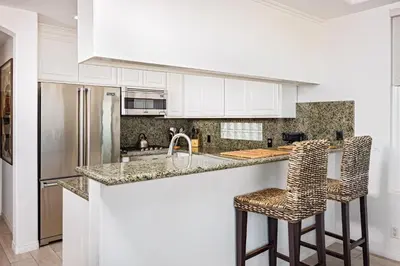 a kitchen with white cabinets and two bar stools at 204 E Oceanfront A in Newport Beach