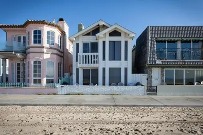 a house on the beach next to two buildings at 3112 W Oceanfront A in Newport Beach