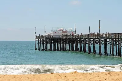 a pier with a boat sitting on top of the ocean at 3112 W Oceanfront A in Newport Beach