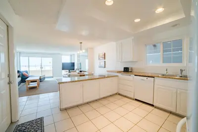 a kitchen with white cabinets and a living room at Abigail - Beachfront in Newport Beach