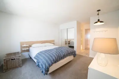 a white bedroom with a bed and a lamp at Abigail - Beachfront in Newport Beach