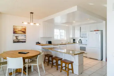 a kitchen with a table and a white refrigerator at Abigail - Beachfront in Newport Beach
