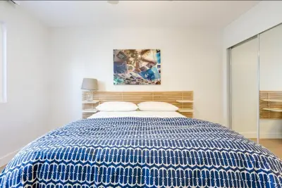 a blue and white bed in a white bedroom at Beatrice - Beachfront in Newport Beach