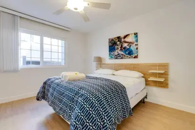a white bedroom with a bed and a ceiling fan at Christina - Beachfront in Newport Beach