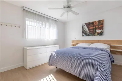 a white bedroom with a bed and a ceiling fan at Alexander - Oceanview in Newport Beach