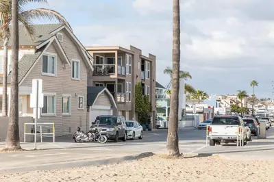 a street with parked cars and a house and palm trees at Daniel - Oceanview in Newport Beach