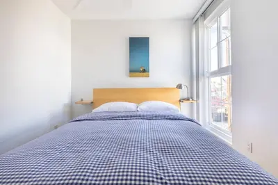 a bed in a white room with a checkered blanket at Daniel - Oceanview in Newport Beach