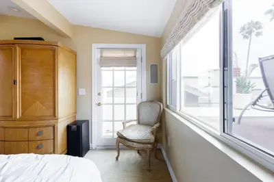 a bedroom with a chair and a large window at Beachfront Home in Newport Beach