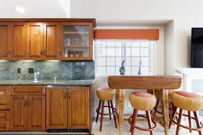 a kitchen with wooden cabinets and bar stools at Beachfront Home in Newport Beach