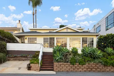 a white house with a palm tree in the background at The Pelican in Encinitas