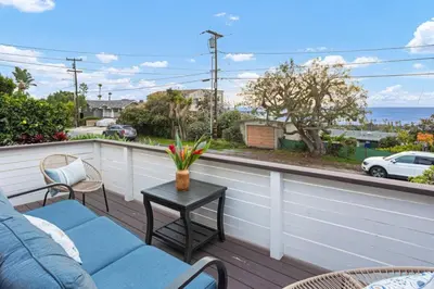 a balcony with a couch and chairs and a view of the ocean at The Pelican in Encinitas