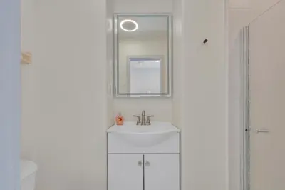 a white bathroom with a sink and a mirror at The Shining Sea Crab in Oceanside