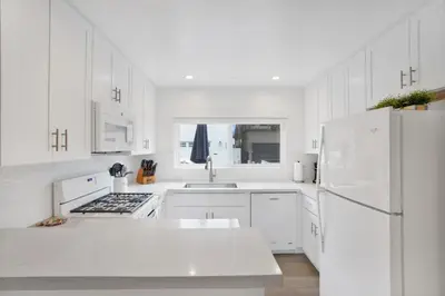 a white kitchen with white cabinets and a white refrigerator at 5408 Seashore Dr A in Newport Beach