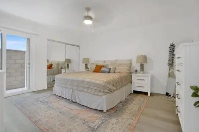 a white bedroom with a bed and a mirror at 5408 Seashore Dr A in Newport Beach