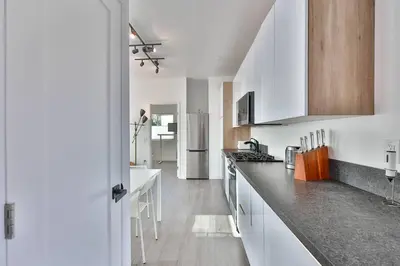 a kitchen with white cabinets and black counter tops at Bungalow near zoo and beach with AC, EV, private yard in San Diego