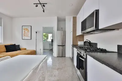 a kitchen with a stove top oven next to a living room at Bungalow near zoo and beach with AC, EV, private yard in San Diego