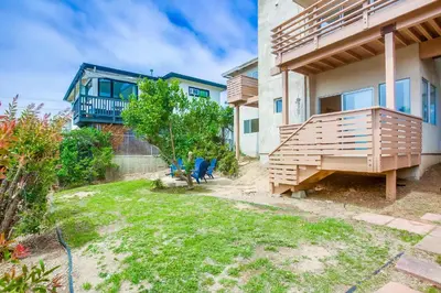 a house with a yard with chairs and a balcony at 100 Yards Ocean & Surfing Ocean Views Backyard in San Diego