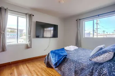 a bedroom with a bed and a tv and windows at Steps 2 Ocean & Surfing Ocean Views Rooftop Deck in San Diego
