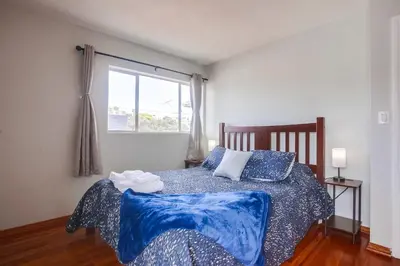 a bedroom with a bed with blue pillows and a window at Steps 2 Ocean & Surfing Ocean Views Rooftop Deck in San Diego