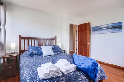 a bedroom with a blue bed with towels on it at Steps 2 Ocean & Surfing Ocean Views Rooftop Deck in San Diego