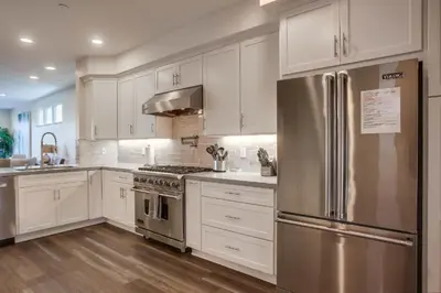 a kitchen with white cabinets and a stainless steel refrigerator at Ocean-view home blocks to beach with private hot tub & rooftop deck in San Diego
