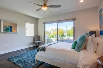 a bedroom with a bed with a ceiling fan and a window at Ocean-view home blocks to beach with private hot tub & rooftop deck in San Diego