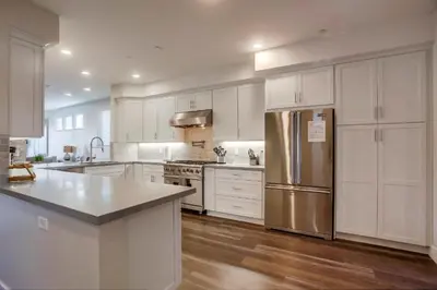 a kitchen with white cabinets and a stainless steel refrigerator at Ocean-view home blocks to beach with private hot tub & rooftop deck in San Diego