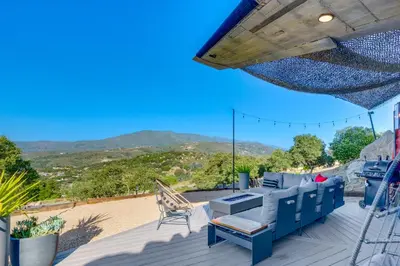 a patio with a blue couch and a chair on a deck at Fallbrook Airplane Home with Fire Pit and Mtn Views! in Temecula