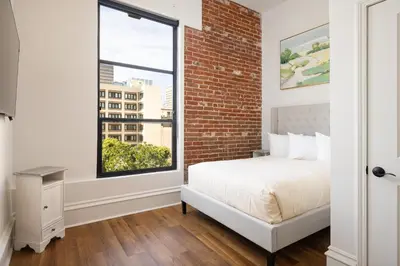 a bedroom with a brick wall and a bed and a window at The Beau Hotel Downtown San Diego Gaslamp Quarter in San Diego