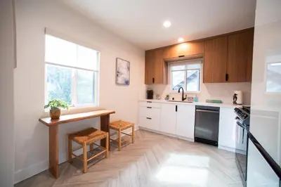 a kitchen with white cabinets and a wooden table at Modern Ocean Beach Apartment in San Diego