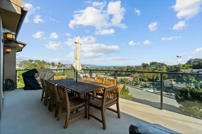 a dining room table with chairs and an umbrella on a balcony at Dana Point Luxe in Dana Point