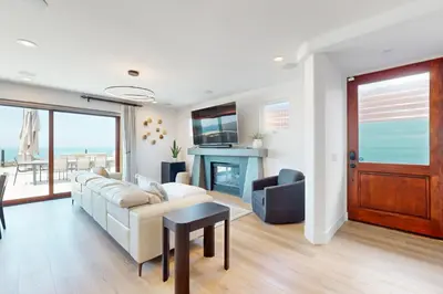 a living room with a couch and a fireplace at Neptune Sunset Shores Oceanfront in Encinitas