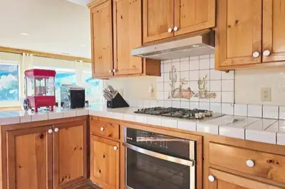a kitchen with wooden cabinets and a stove top oven at Panorama Paradiso by CasadeLuz, 5Acre 360 Retreat close to Old Town Temecula Wine Country in Temecula