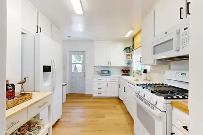 a white kitchen with white cabinets and white appliances at Blue Oasis Cozy Home in San Diego