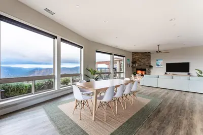 a dining room with a table and chairs and windows at Vista Grande home in Ramona