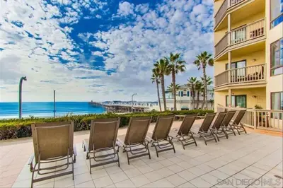 a row of chairs on a patio near the beach at Beach Front Bliss - Entire Condo - Crystal Pier in San Diego