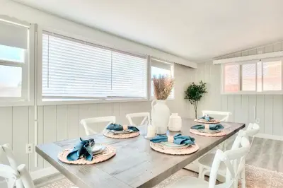 a dining room with a wooden table and white chairs at Beachside Bliss Spacious 3BR Retreat, Steps to Ocean in Oceanside