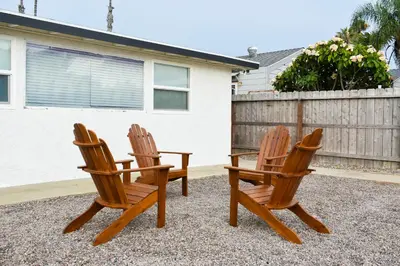 two wooden chairs sitting next to a fence at Beachside Bliss Spacious 3BR Retreat, Steps to Ocean in Oceanside