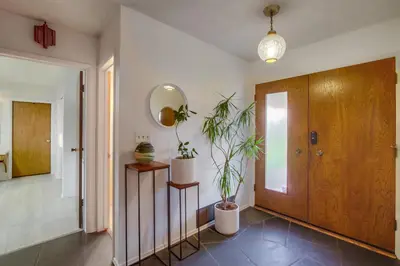 a hallway with a mirror and two plants in it at Red Hawk Coastal Estate in San Diego