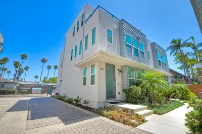 a white building with blue windows on a street at Blocks To Beach - Coastal Beach Decor - Garage Parking - Gated Community - 30 Day Fully Furnished in Oceanside