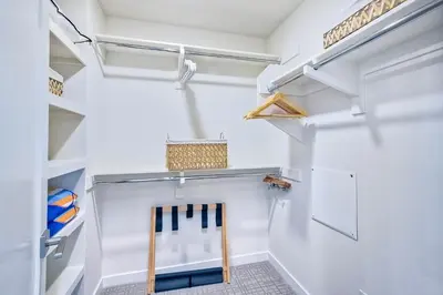 a walk in closet with white walls and shelves at Blocks To Beach - Coastal Beach Decor - Garage Parking - Gated Community - 30 Day Fully Furnished in Oceanside