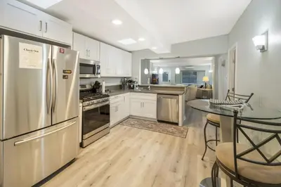 a kitchen with stainless steel appliances and a table at Sunlit Shores beachside Bliss in San Diego
